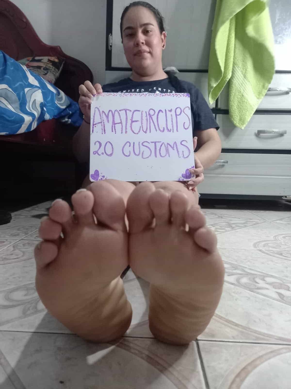 Girl with dark hair holding a sign, feet close-up, indoor scene, casual attire.