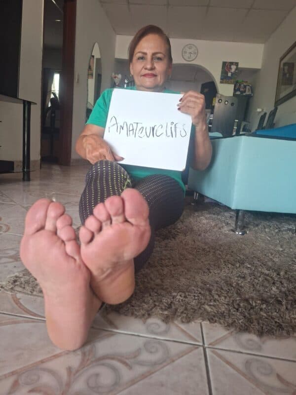 Woman with brown hair, wearing a teal shirt, sitting cross-legged on the floor.
